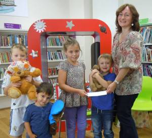 Aimee Edwards, winner of Llanelli Library’s Mythical Maze treasure hunt, receiving her prize from author Wendy White.